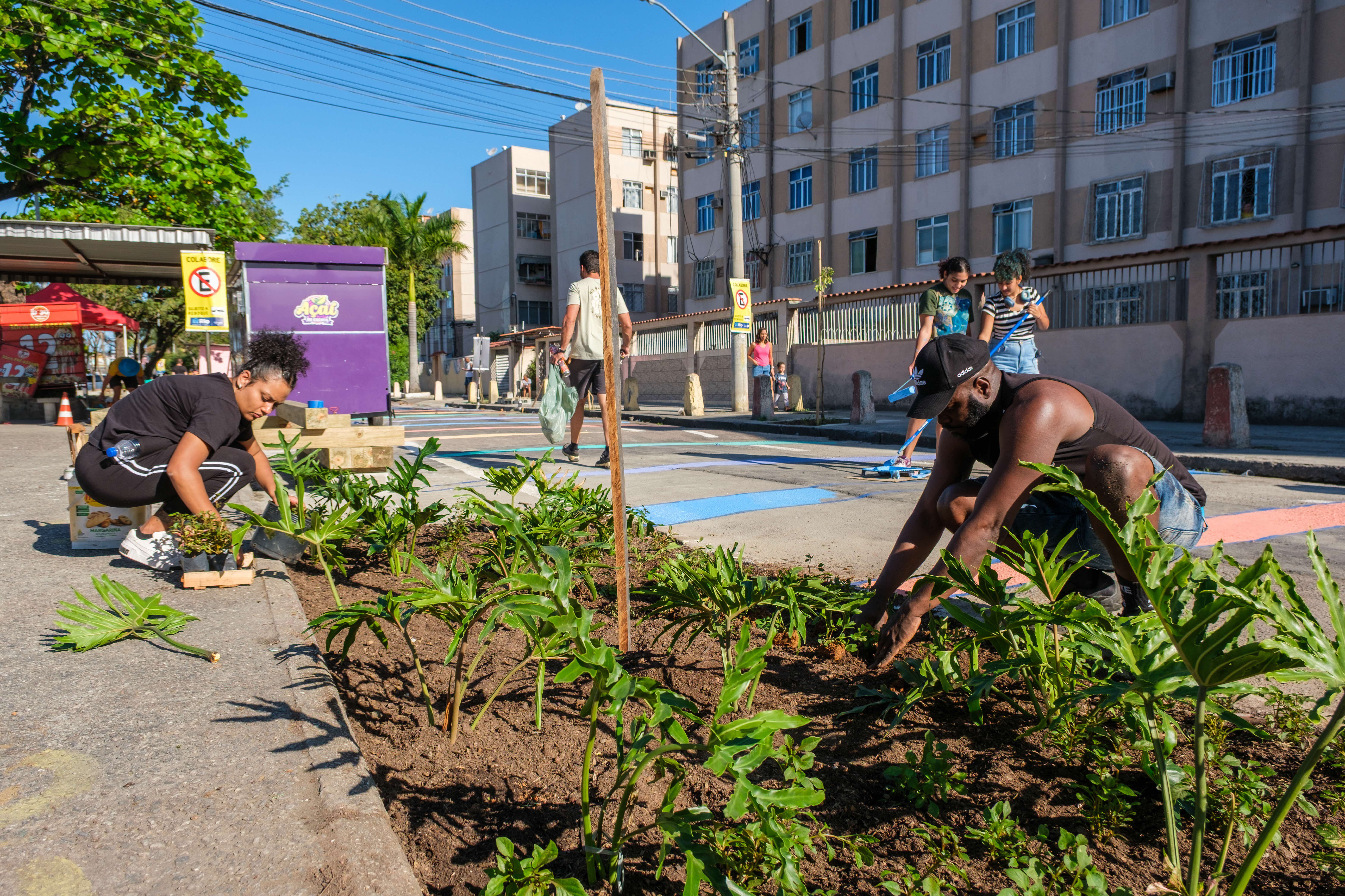 Photo of people taking care of a small garden by the side of a road